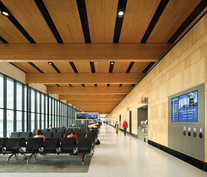 Passengers land and enter into a lounge filled with natural light, enhancing the warmth of the exposed wood ceiling. A wood-clad service wall incorporates information screens, refuse containers and doorways, reducing visual clutter.