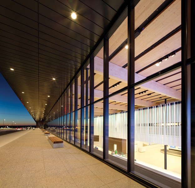 An upper-level roadway for passenger drop-offs offers views into the double-height arrivals hall.