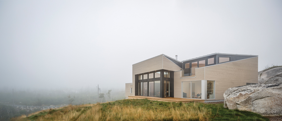 The exterior is clad with gray-washed boards to match the surrounding rocks