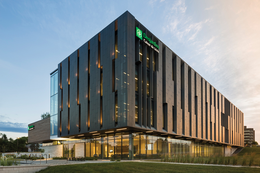A rhythmic façade composed of zinc panels provides filtered light to the office spaces within, while giving the banking headquarters
a handsome street presence. Landscaping softens the site’s slope to create a welcoming approach for clients.