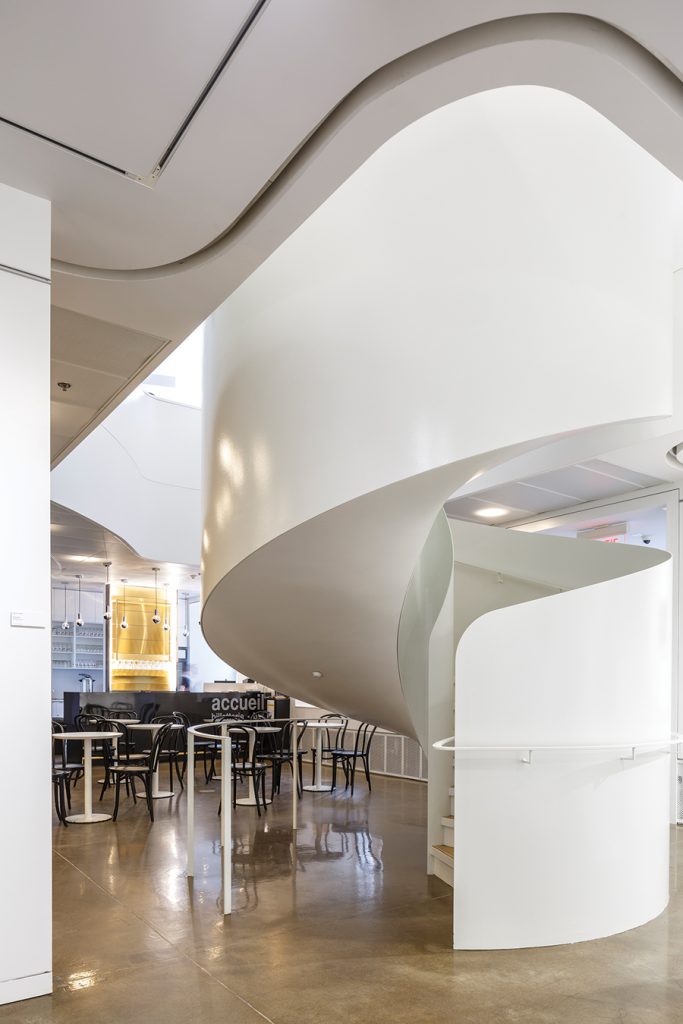 The spiral stair at the edge of the café ascends to the main reading areas on the second floor.