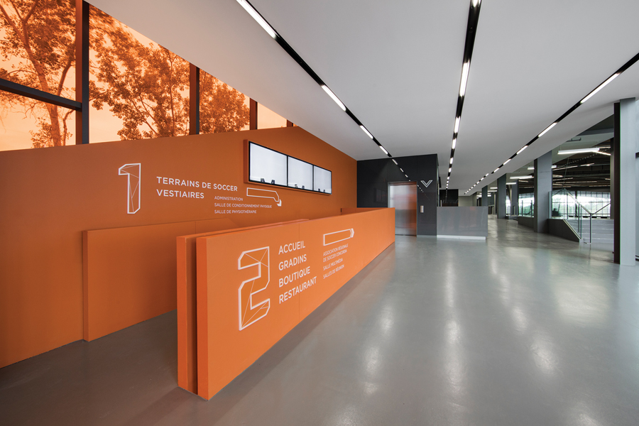 Orange accents at the entrance pick up on the warmth of the wood ceiling above the field.