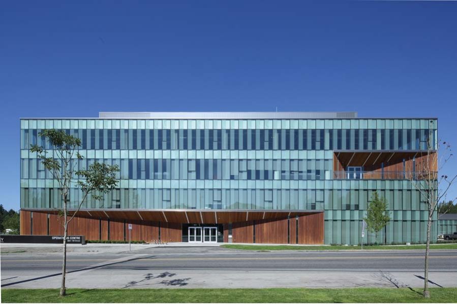 Angled, cedar-lined openings mark the entrances to the Surrey Operations Centre as well as upper floor balconies on all sides of the office block. The stripped-down material palette of wood, glass and steel is used throughout the complex’s service and storage buildings.