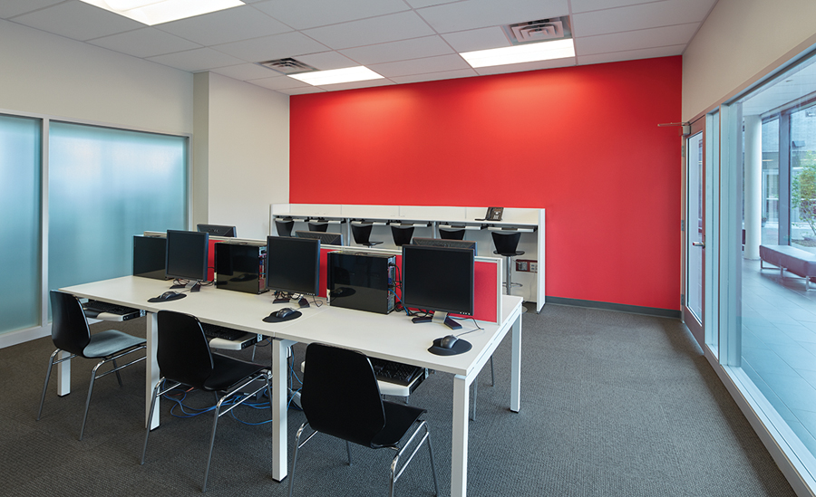 Glazed interior walls bring daylight into a computer room, adjacent a corridor that doubles as a walking circuit. Photo by Shai Gil