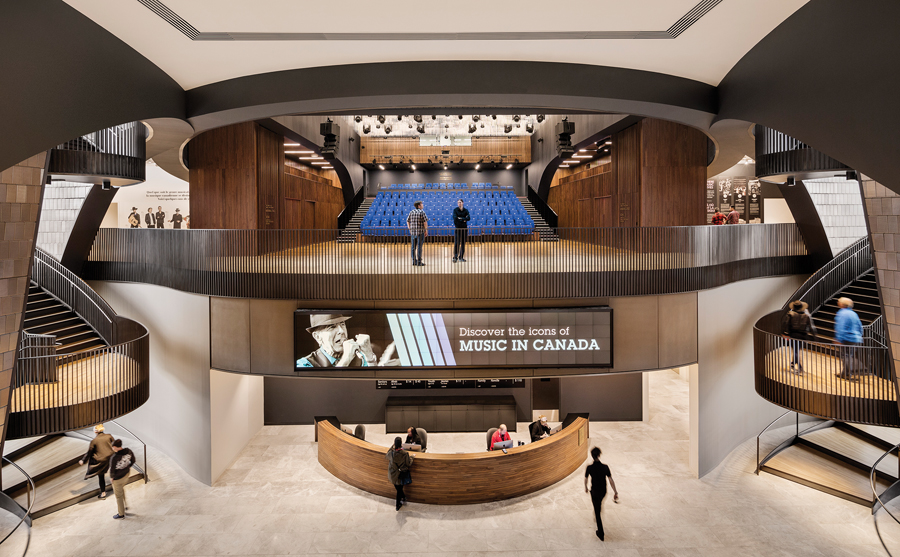 The main performance hall overlooks Studio Bell’s lobby, creating a music festival atmosphere where performance and sound fill the air. A pair of helical stairs flanks the lobby.