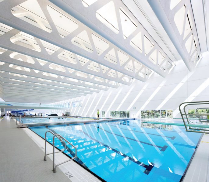 Large wood trusses cast striking patterns of light and shadow across the space, while doubling as accessways for servicing the lights and fans. Photo: Ema Peter