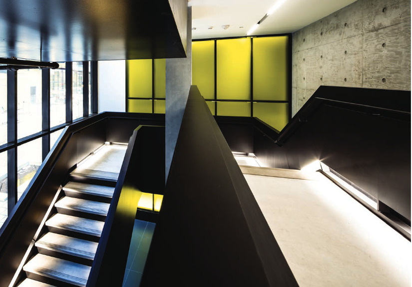 The interiors include dramatic staircases and common areas overlooking a shared courtyard. Diverse unit layouts accommodate a range of residents.