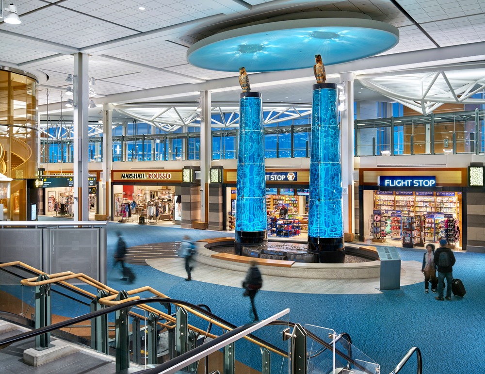 Vancouver International Airport A-B Connector - The glass totem artworks and "sky" above are illuminated by internal 4000K LED spotlights and the Eagles are illuminated by RGBW LED projectors with gobos. Photo credit: Ed White Photography