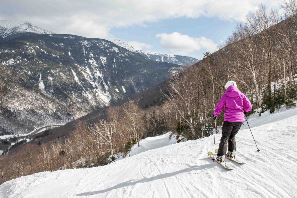 A person in a pink coat skiing at Cannon Mountain, New Hampshire