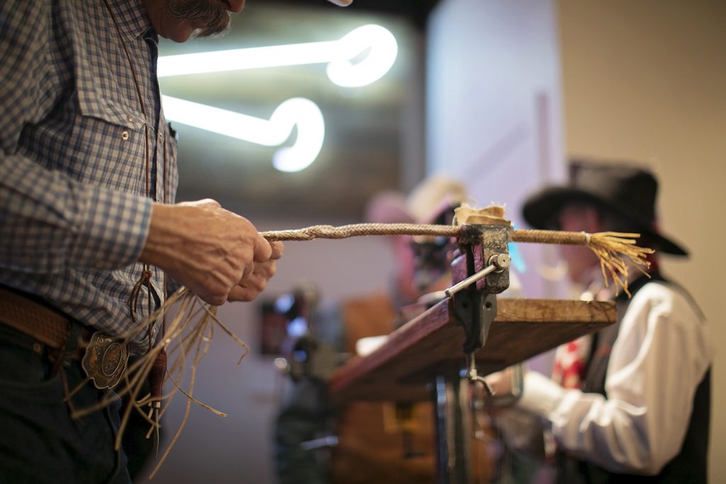 A man demonstrates the technique of rawhide braiding