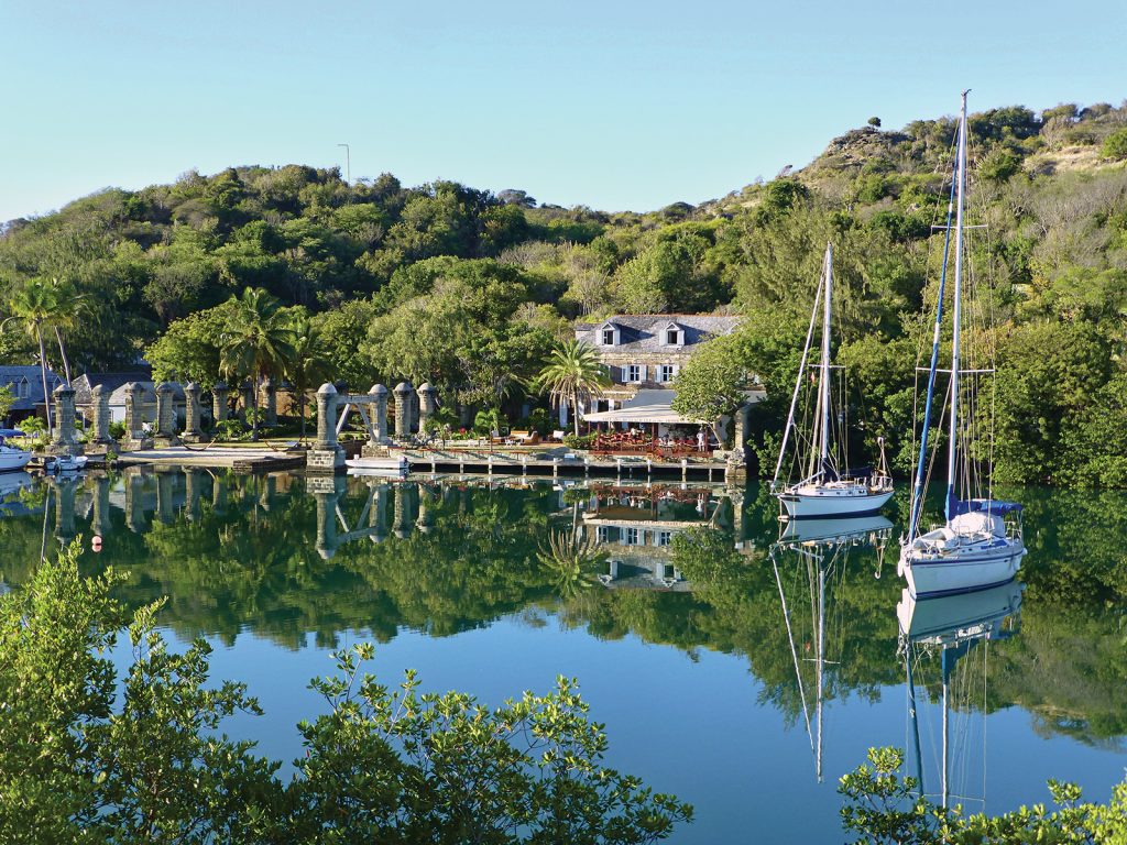 A peaceful tropical lagoon surrounded by lush trees, with sailboats at anchor