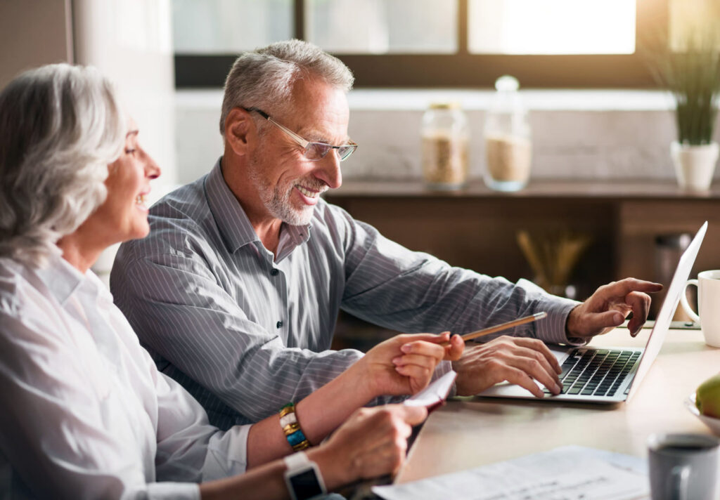 Elderly couple sitting in front of a notebook computer