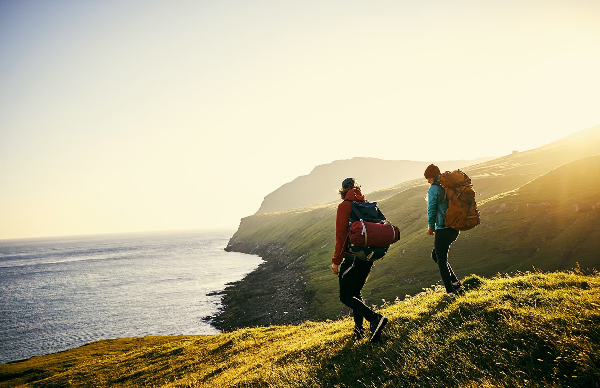 Backpacker travel insurance for two people hiking on cliffs near water