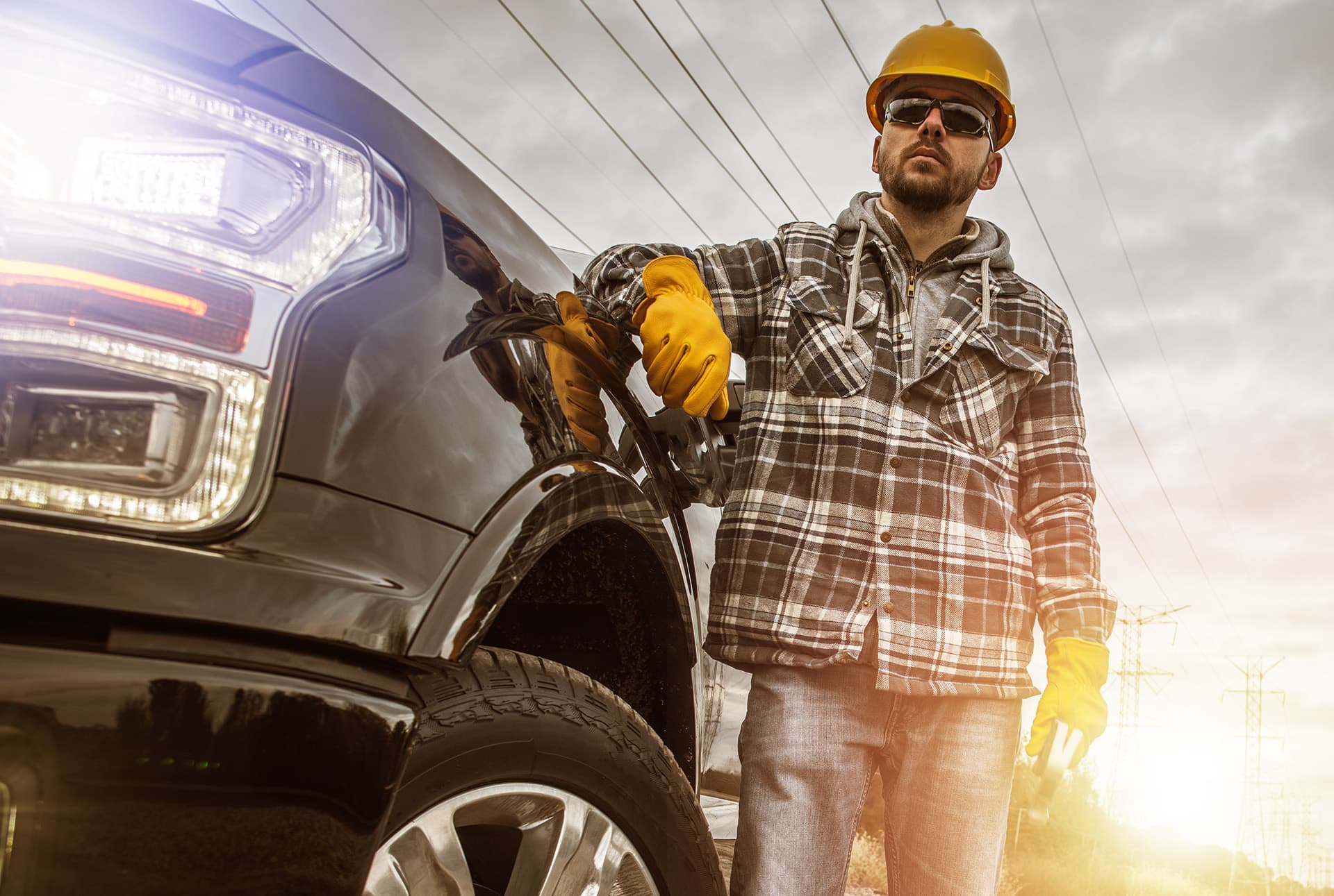 Commercial auto insurance for a man wearing a hard hat and gloves leaning on his truck