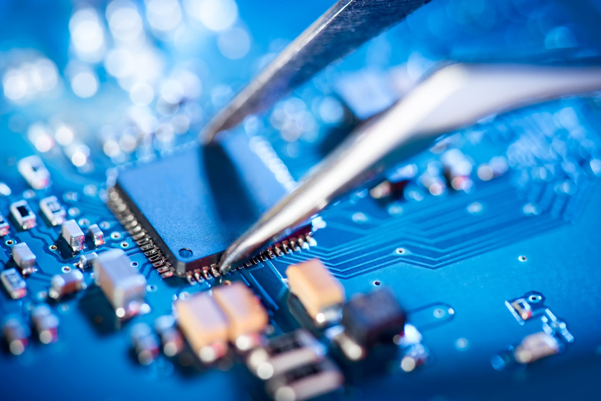 Tweezers grabbing something off of a mother board covered by equipment breakdown insurance