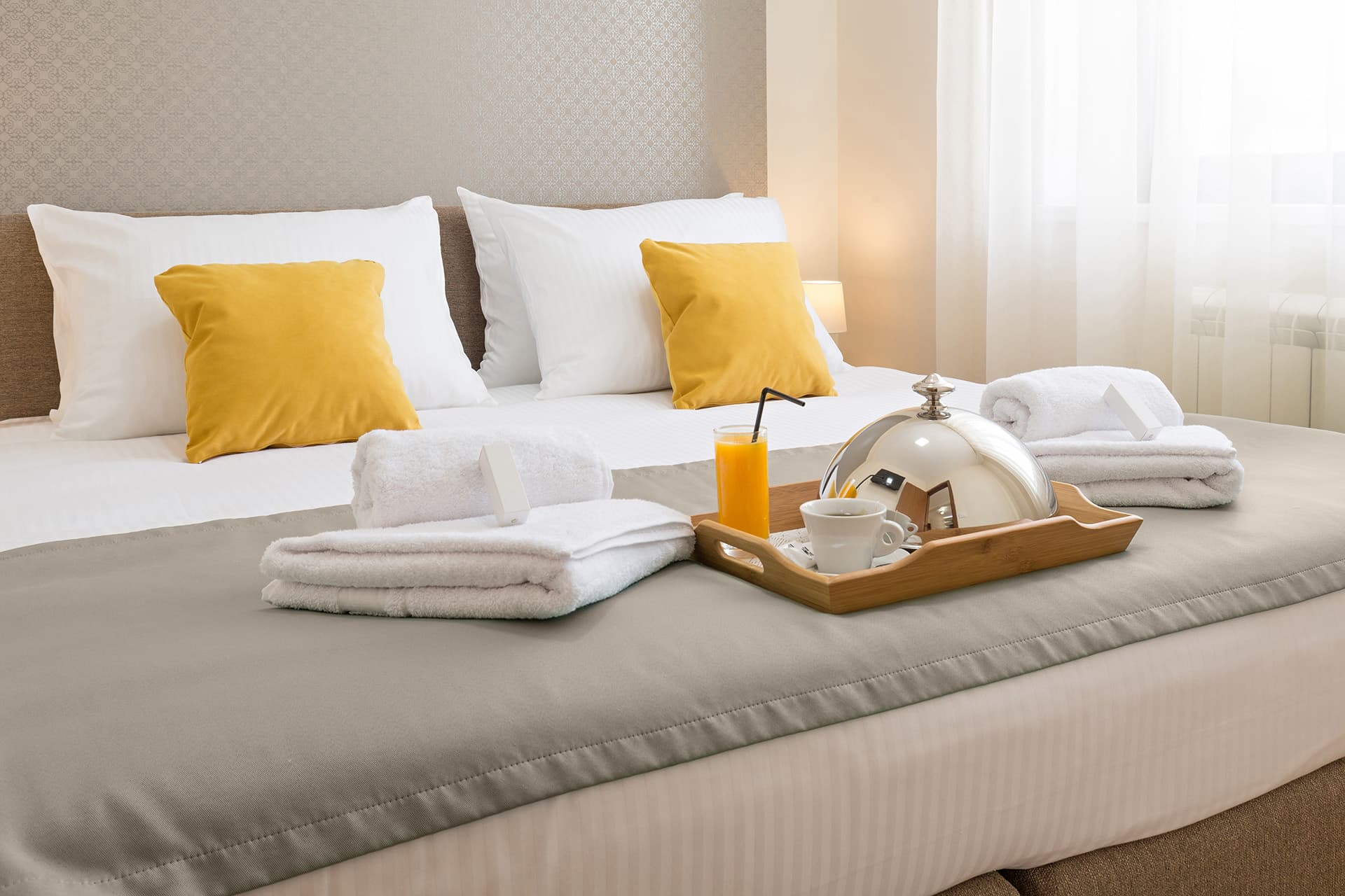 Bed with towels and room service tray at a hotel with hotel insurance