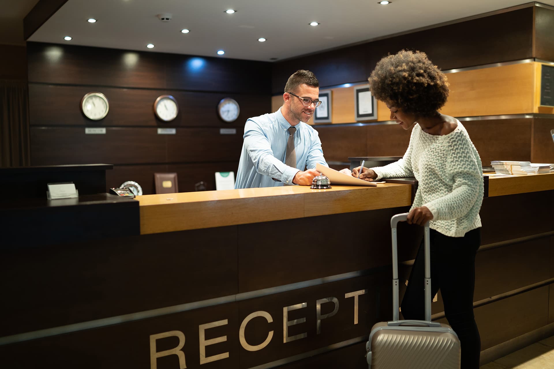 Man at a reception desk helping a woman checking into a hotel with hotel insurance
