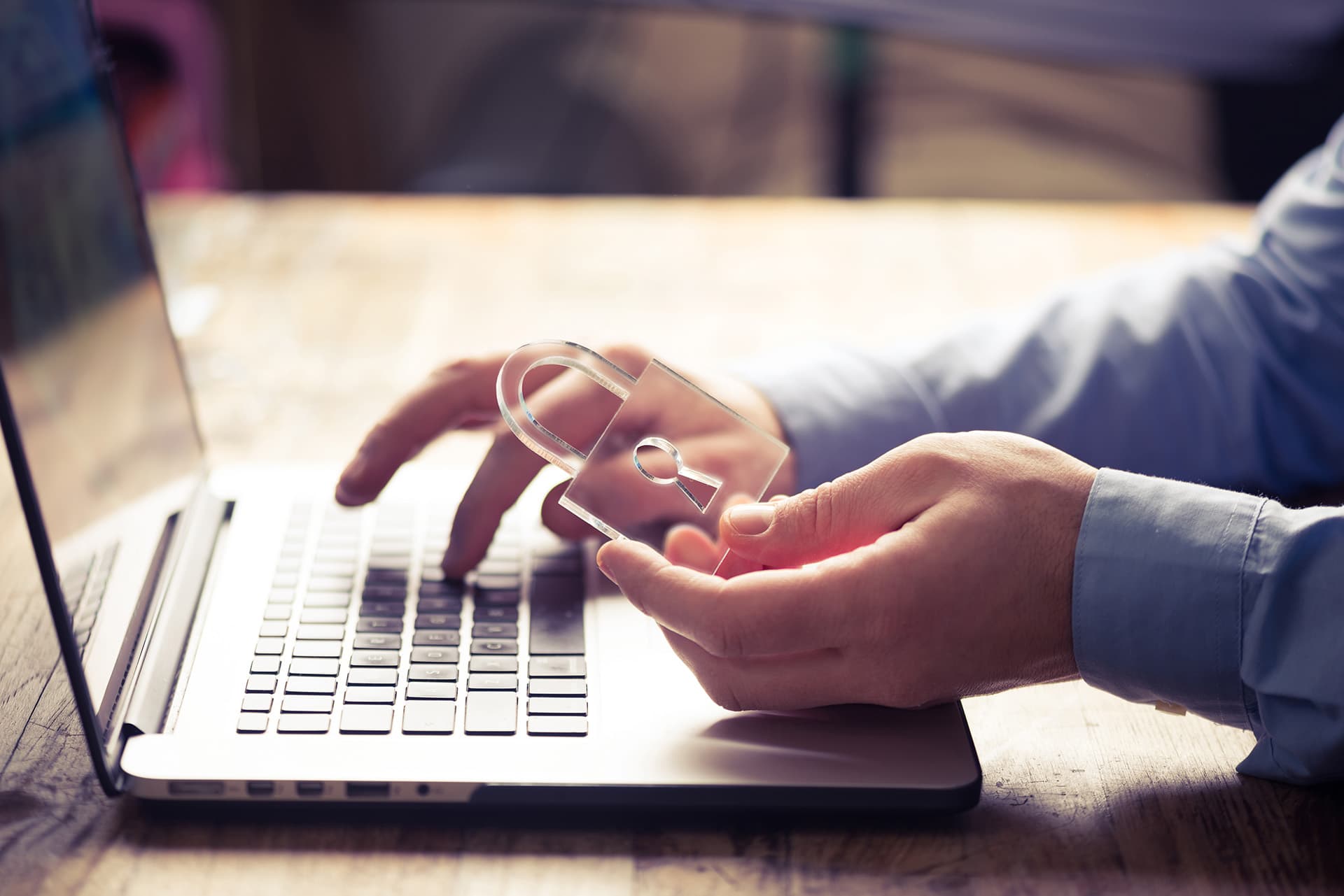 Identity theft insurance for man sitting at his laptop, holding a clear plastic lock