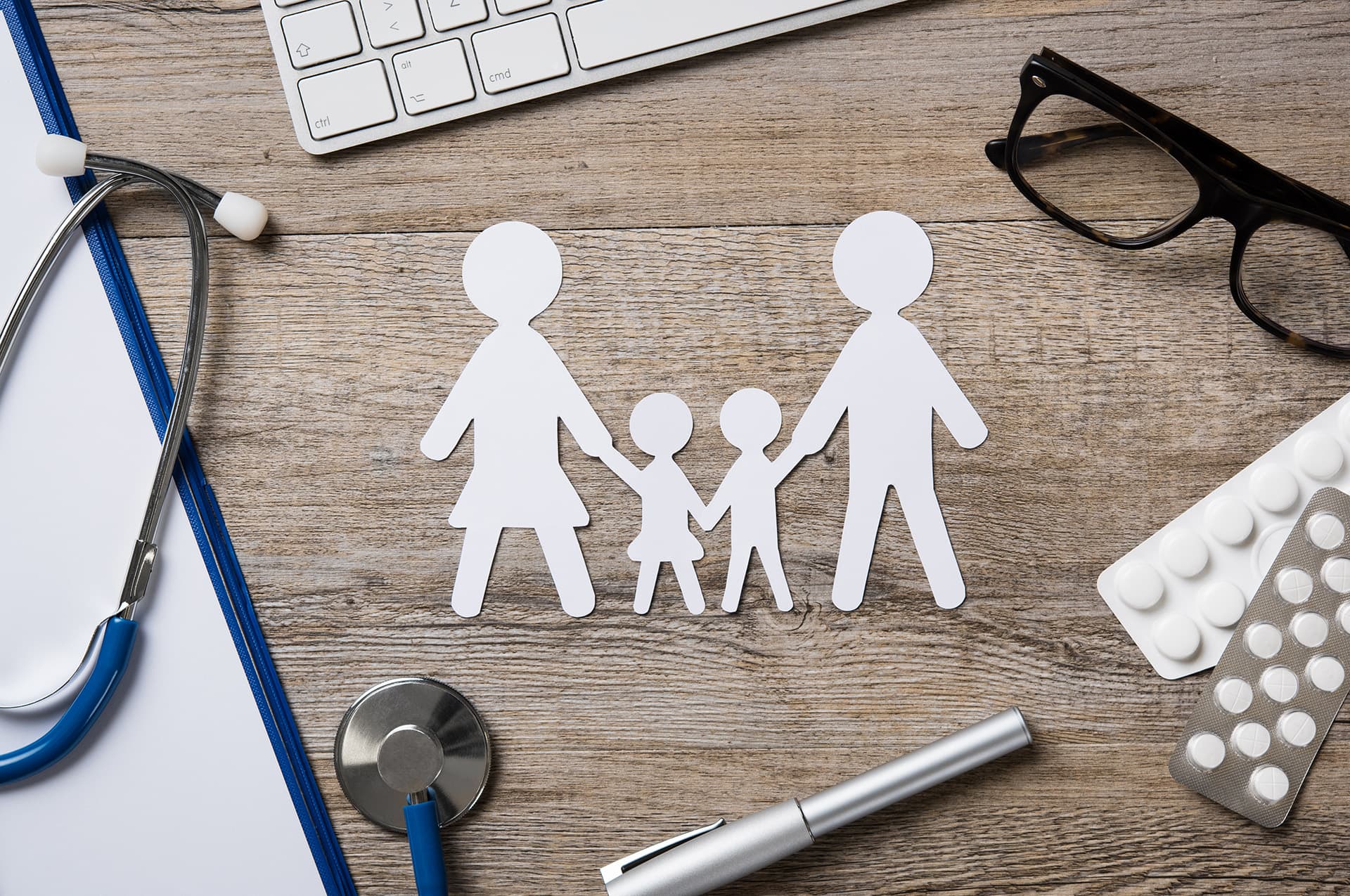 Paper cut out of family on a doctor's desk with professional liability insurance