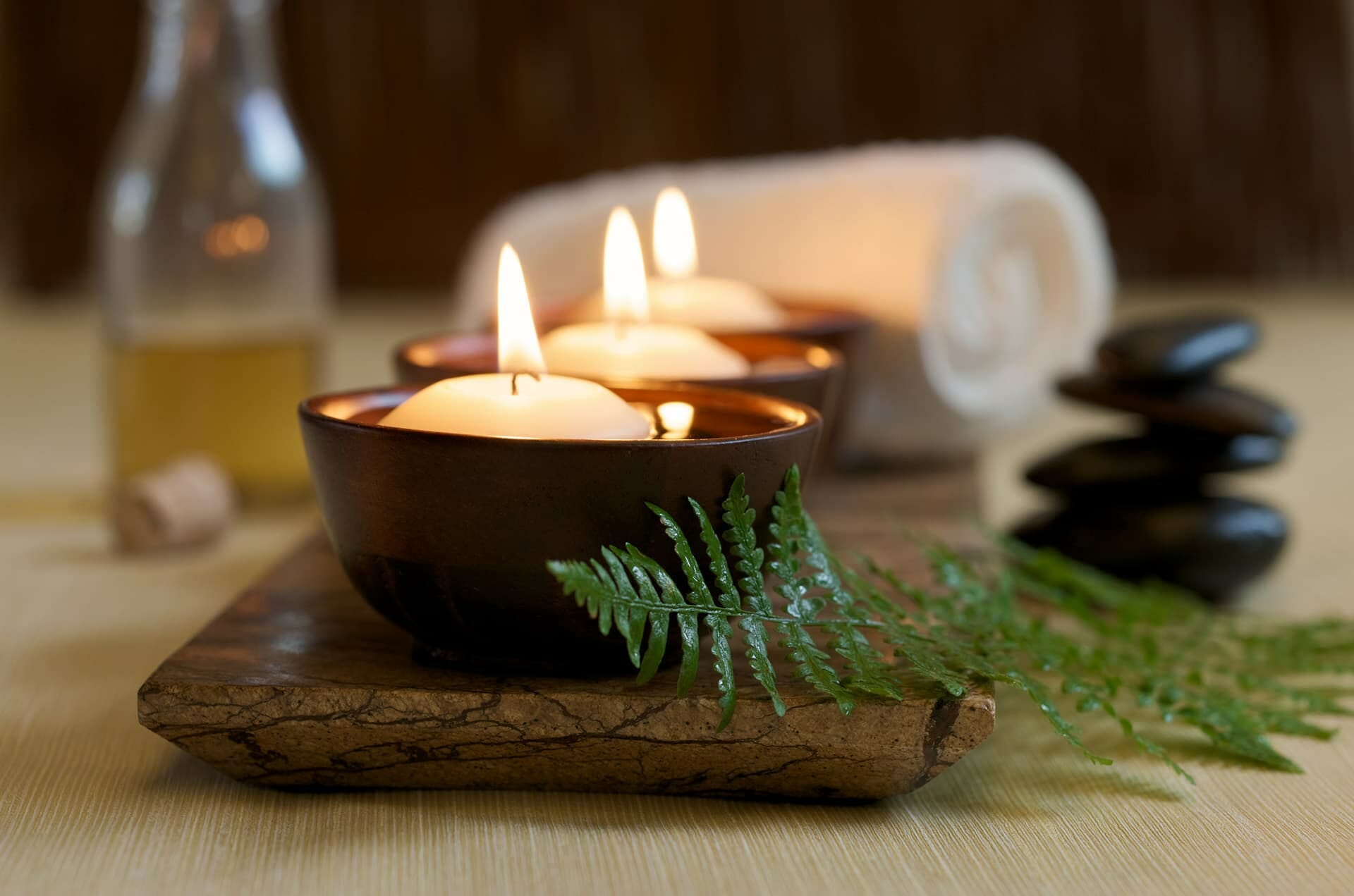 Candles, hot stones, oil and a towel at a spa with spa insurance