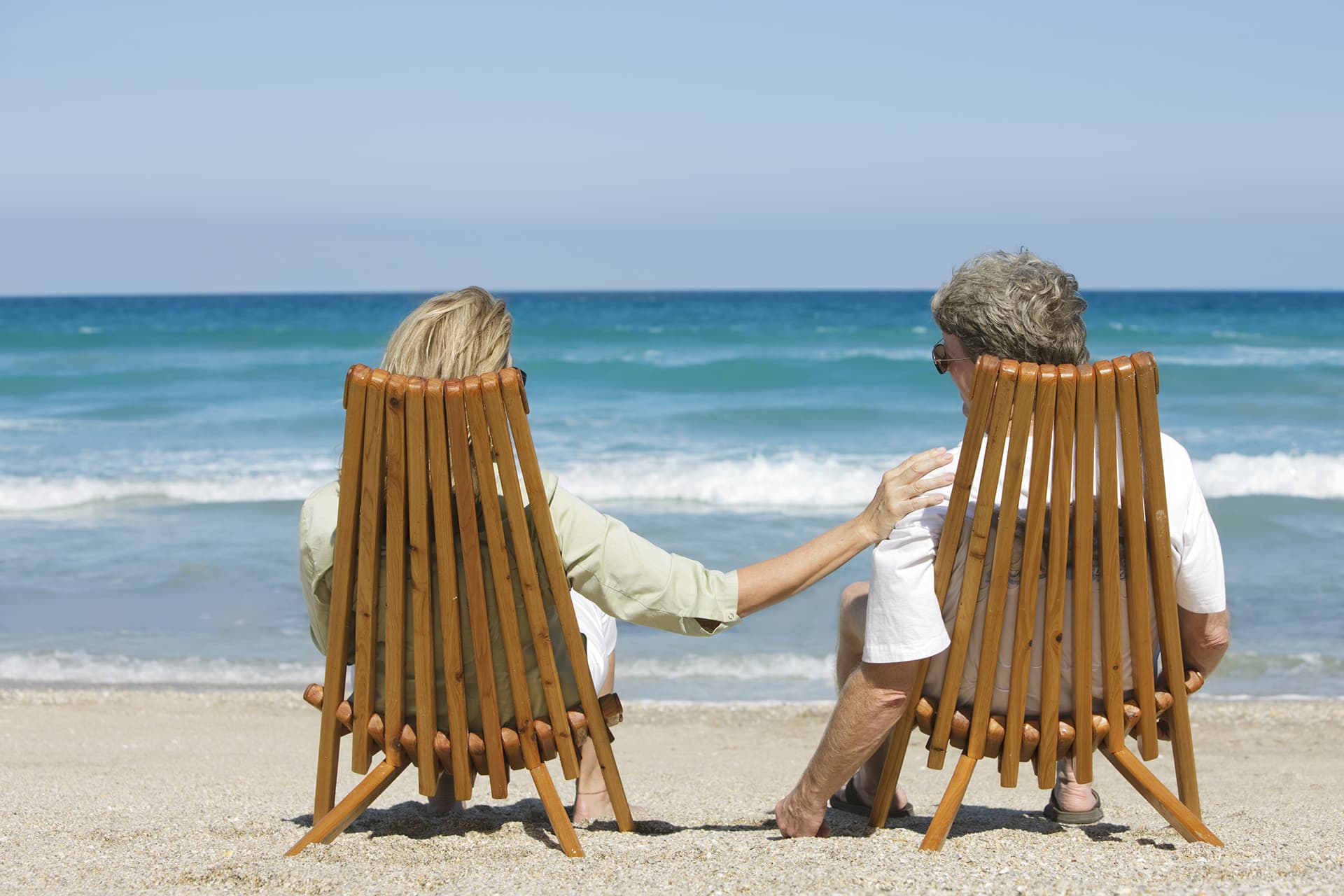 Couple sitting in chairs on a beach with special limits insurance