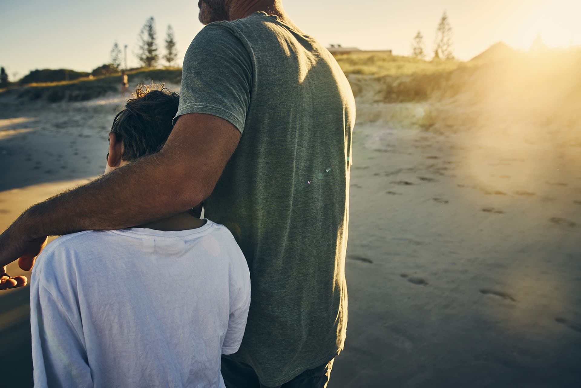 Universal life insurance for a father with his arm around his son walking on sand