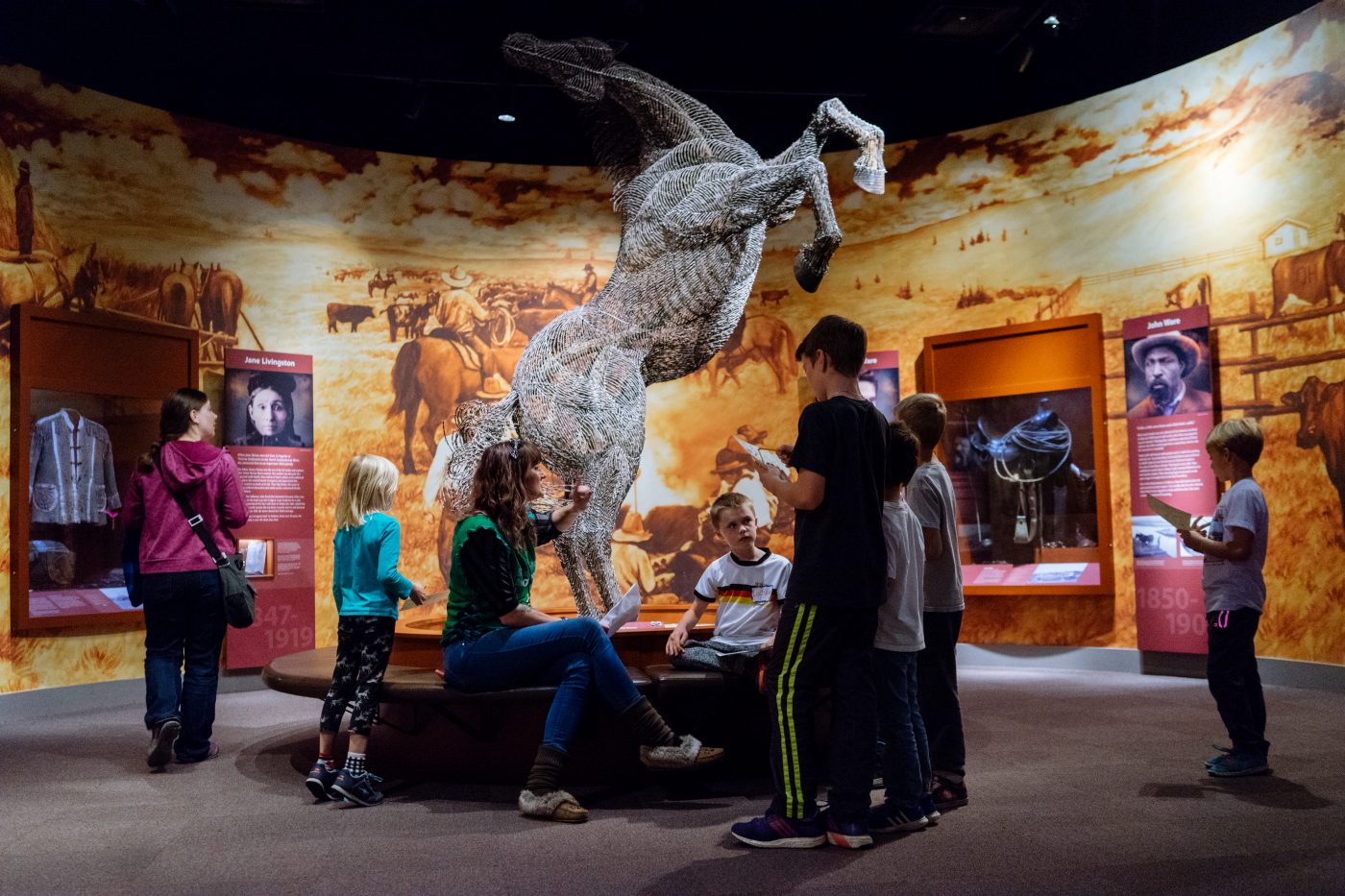 Woman and children gather around horse sculpture