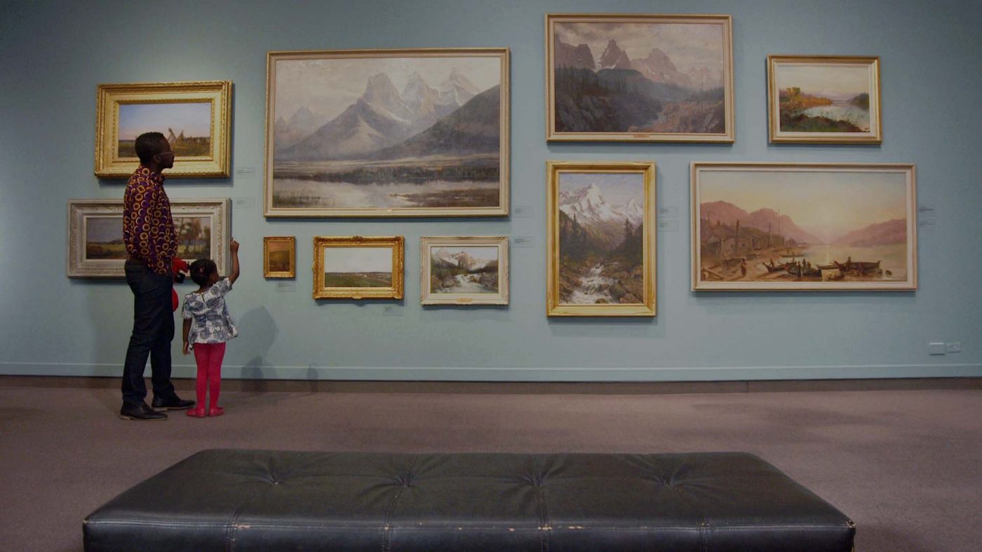 Family looks at framed images in Glenbow gallery