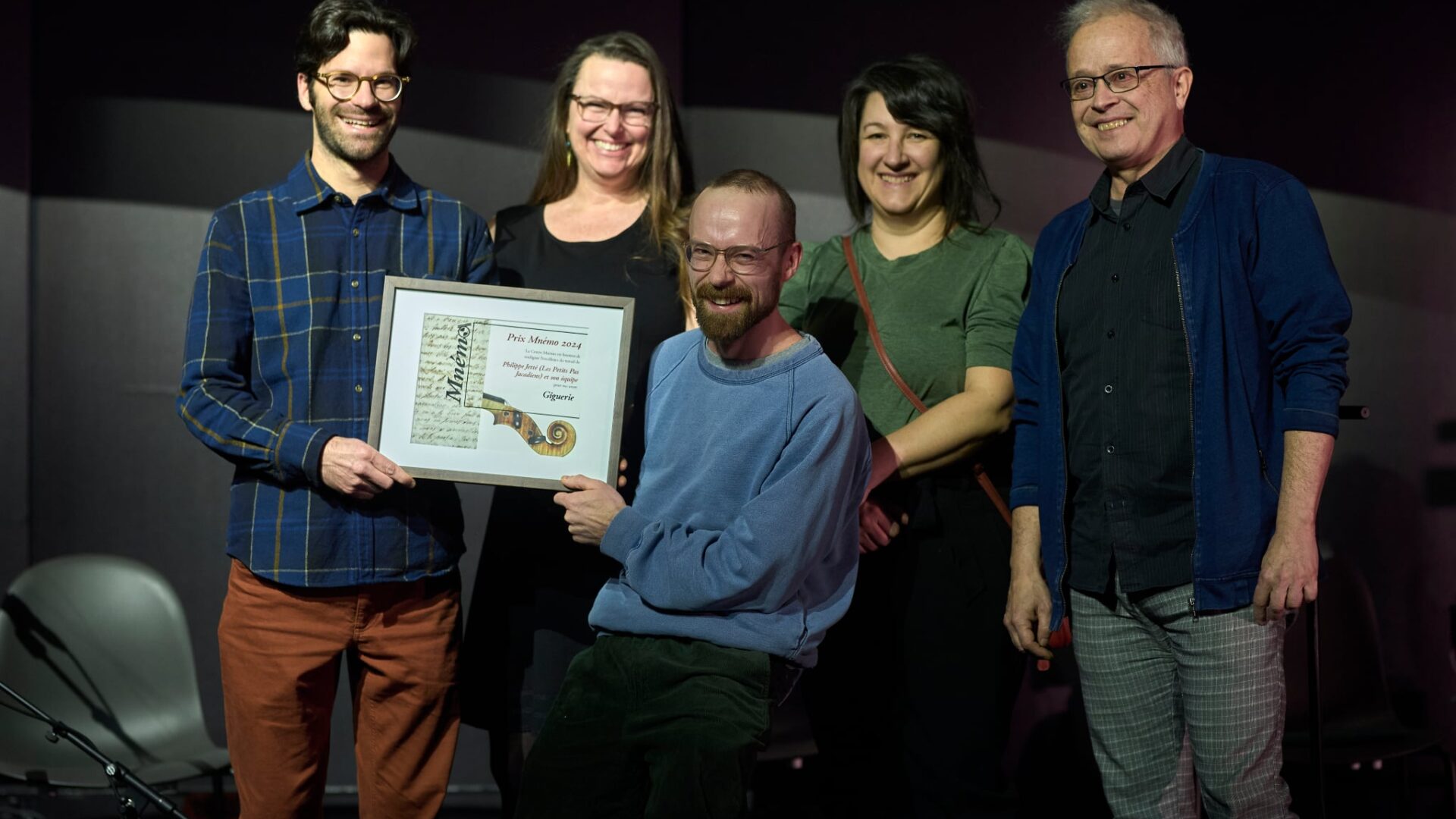 Philippe Jetté (président de Les Petits Pas Jacadiens) reçoit le Prix Mnémo pour le projet Giguerie, accompagné de Véronique Papillon, Mélody Clermont, et Pierre Chartrand, qui ont collaboré au projet (parmi tant d’autres). À l’avant, Antoine Turmine (président du Centre Mnémo) qui remet le Prix. (Photo gracieuseté – Guillaume Morin)