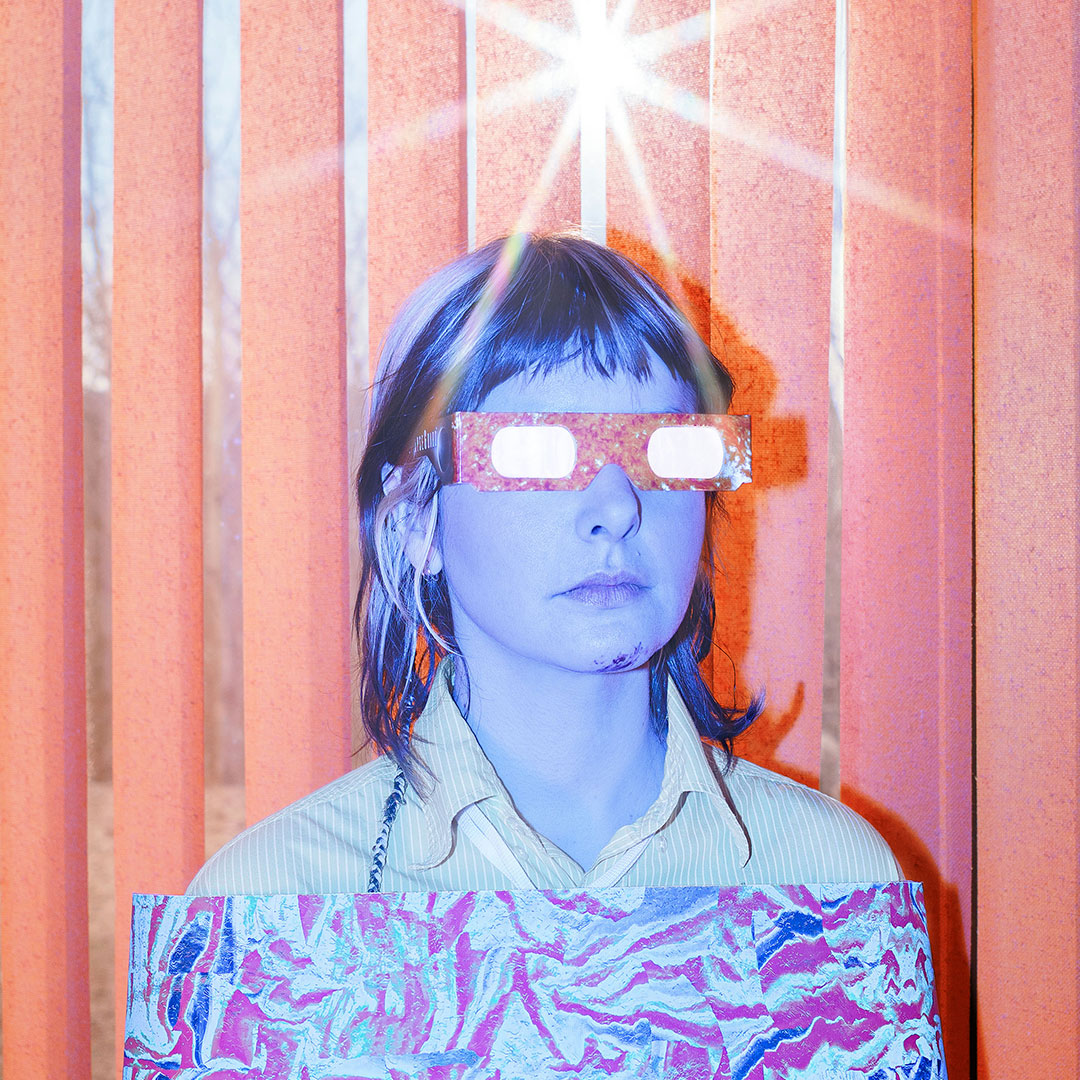 L'artiste Klô Pelgag, lunettes d'éclipse solaire sur les yeux, l'air sérieux.
