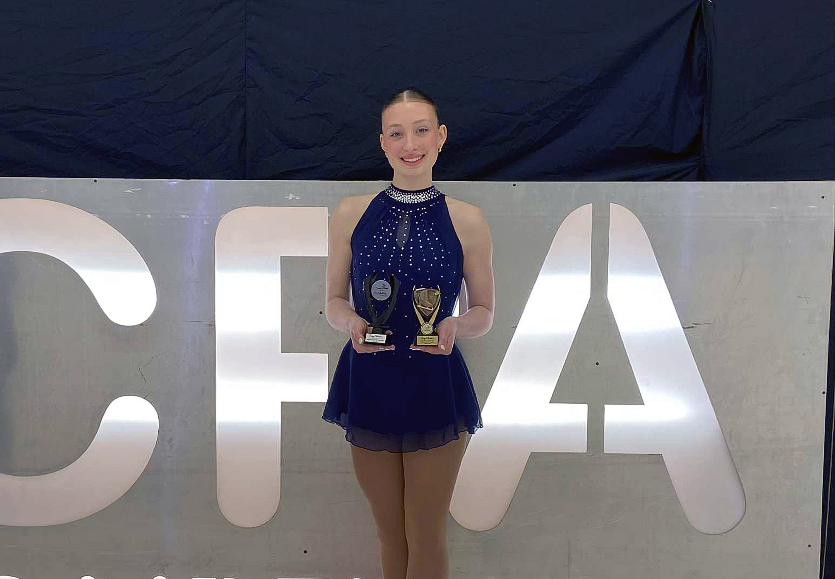 Jeune patineuse tenant deux trophés