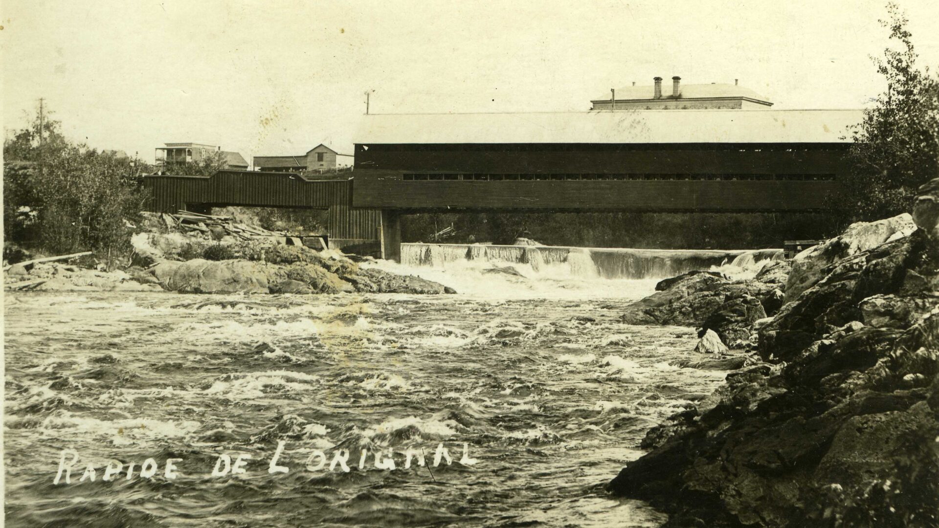 Vue sur la rivière du Lièvre et sur le pont Allard (aujourd'hui le pont Reid) à Mont-Laurier. Vers 1900.
Photo gracieuseté - Société d’histoire et de généalogie des Hautes-Laurentides
