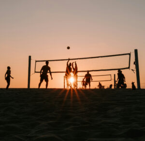 Au coucher du soleil, des adultes jouent au volleyball de plage.