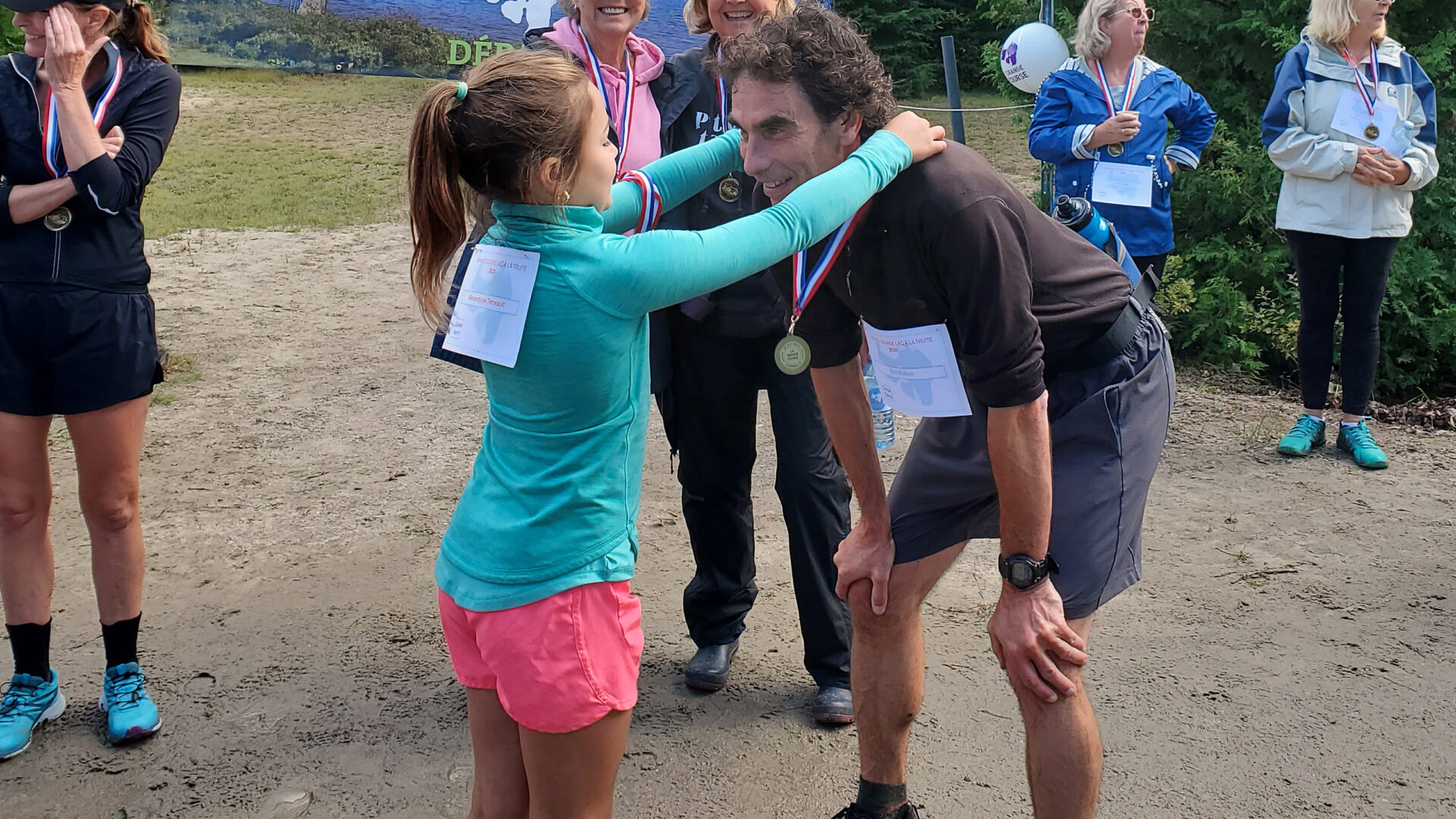 Remise de sa médaille au directeur de l’école La Relève, Éric Dubuc, qui a couru le 15 km sentier, par Alexandrine 7 ans qui a pris part à la course 1km sur route. Derrière, chandail rose, Gertrude St-Laurent, bénévole pour le Club des petits-déjeuners et Nicole Simard-Laurin, responsable du Club des petits-déjeuners de l’école La Relève.
(Photo gracieuseté)