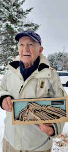 Un vieil homme habillé pour l'hiver, tient un prix dans ses mains.