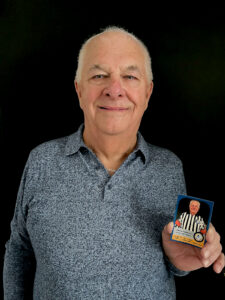 Homme de face souriant avec une carte de hockey à son effigie
