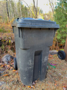 Bac à déchets noir usé dans une entrée