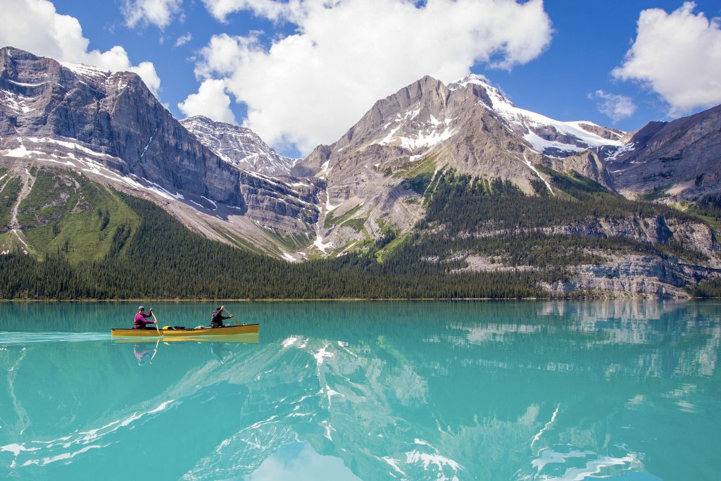 a group of people boating on maligne lake in a canoe and a kayak
