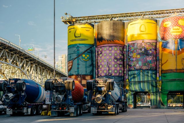 Towering cement silos at Ocean Concrete with two cement trucks.