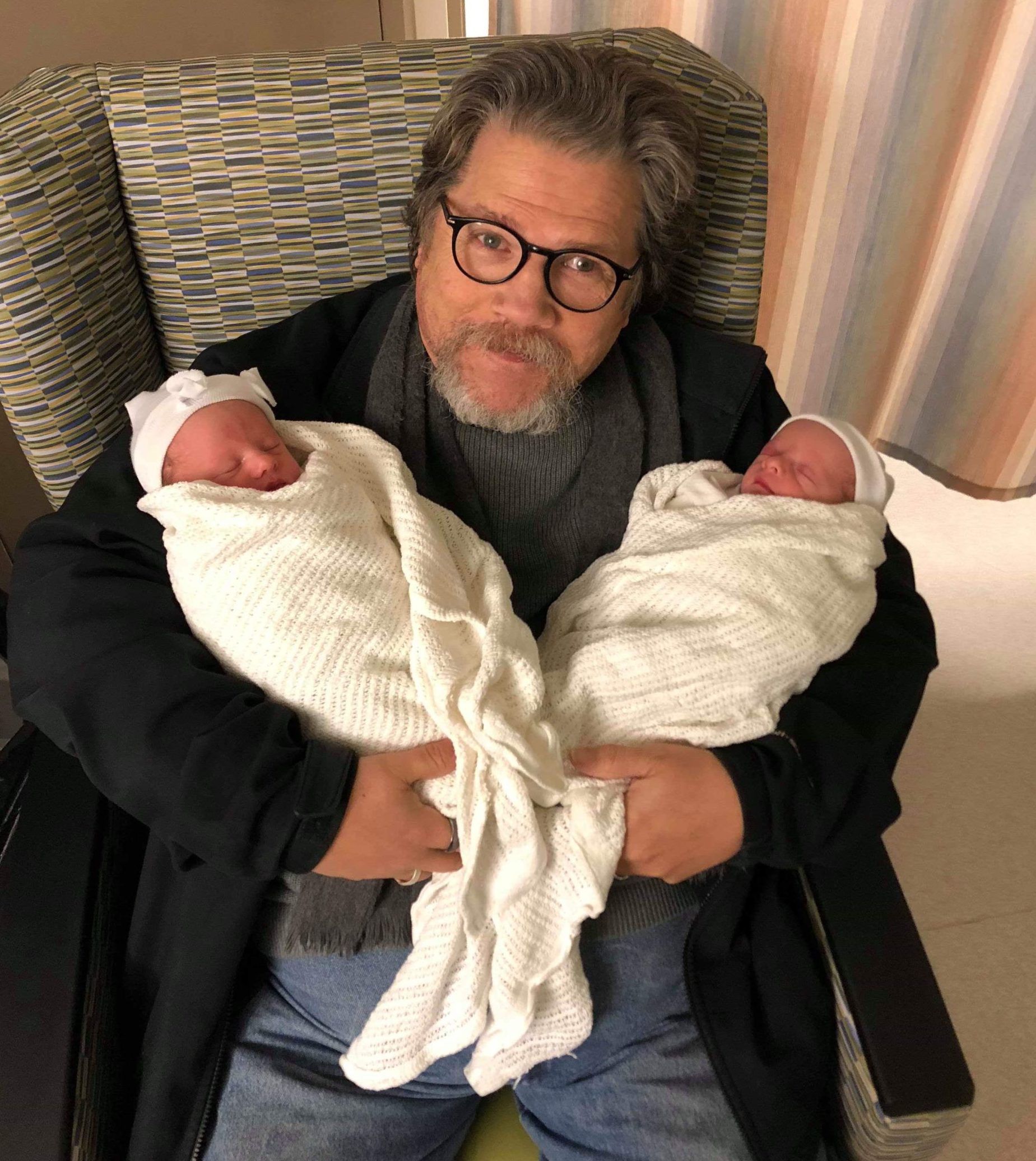 Lance beams up at the camera while holding twin babies - his grandchildren.