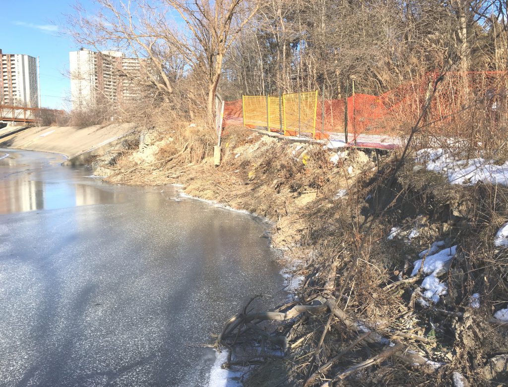 Looking upstream at bank erosion on right side and temporary fencing along eroded trail.