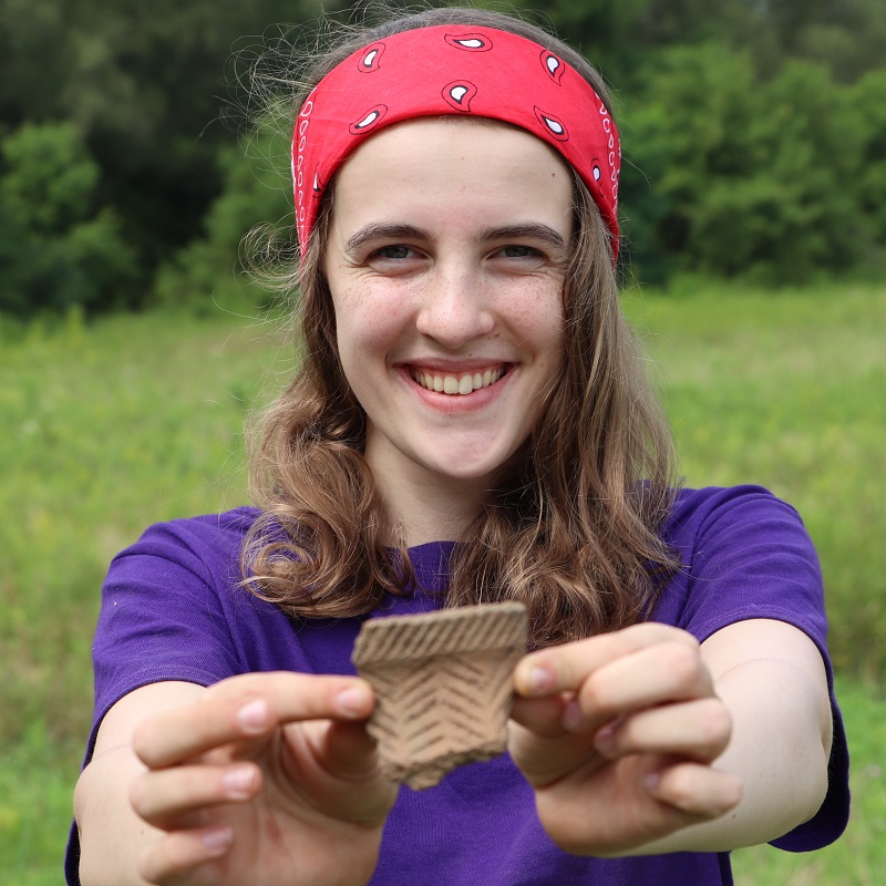 Boyd Archaeological Field School student displays artifact at dig site