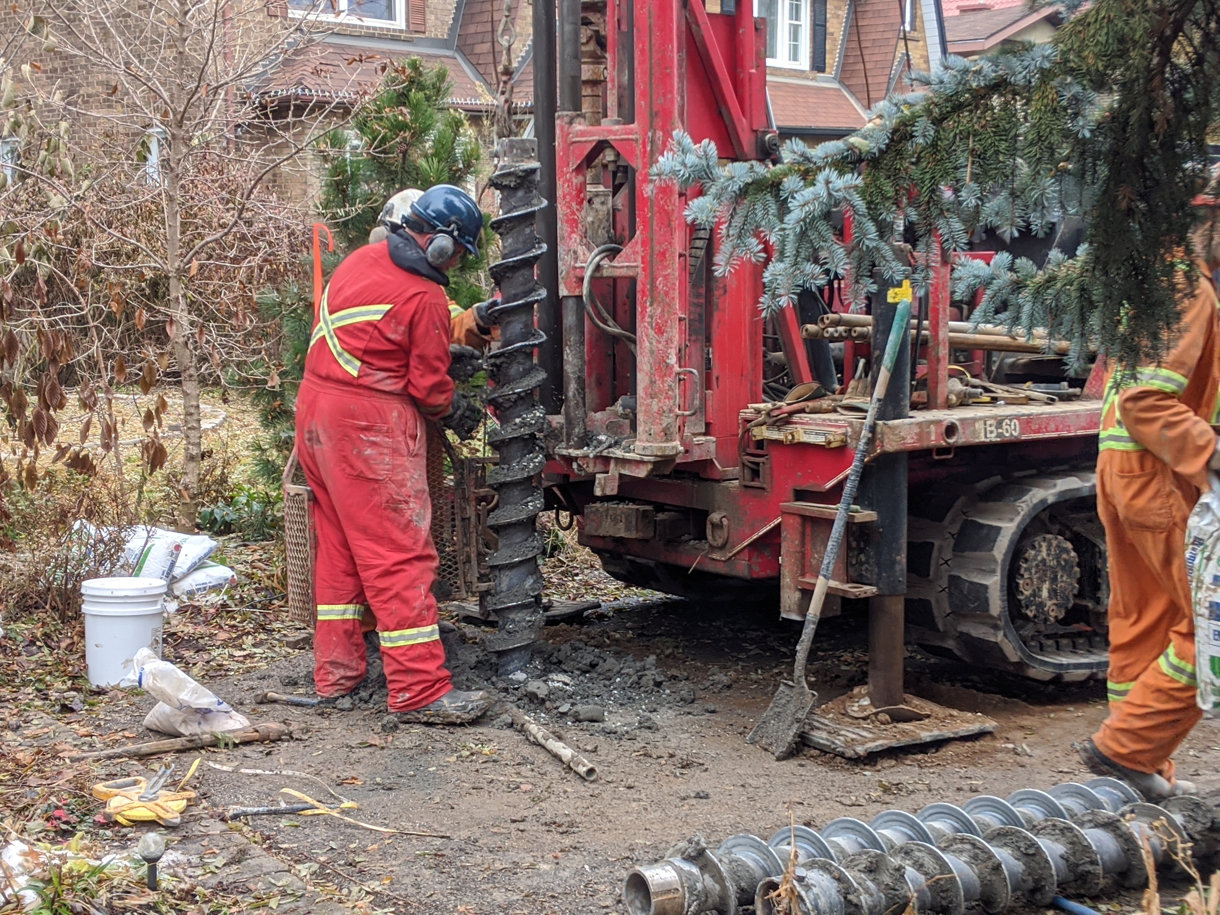 A borehole drill being operated by workers in jumpsuits and hard hats