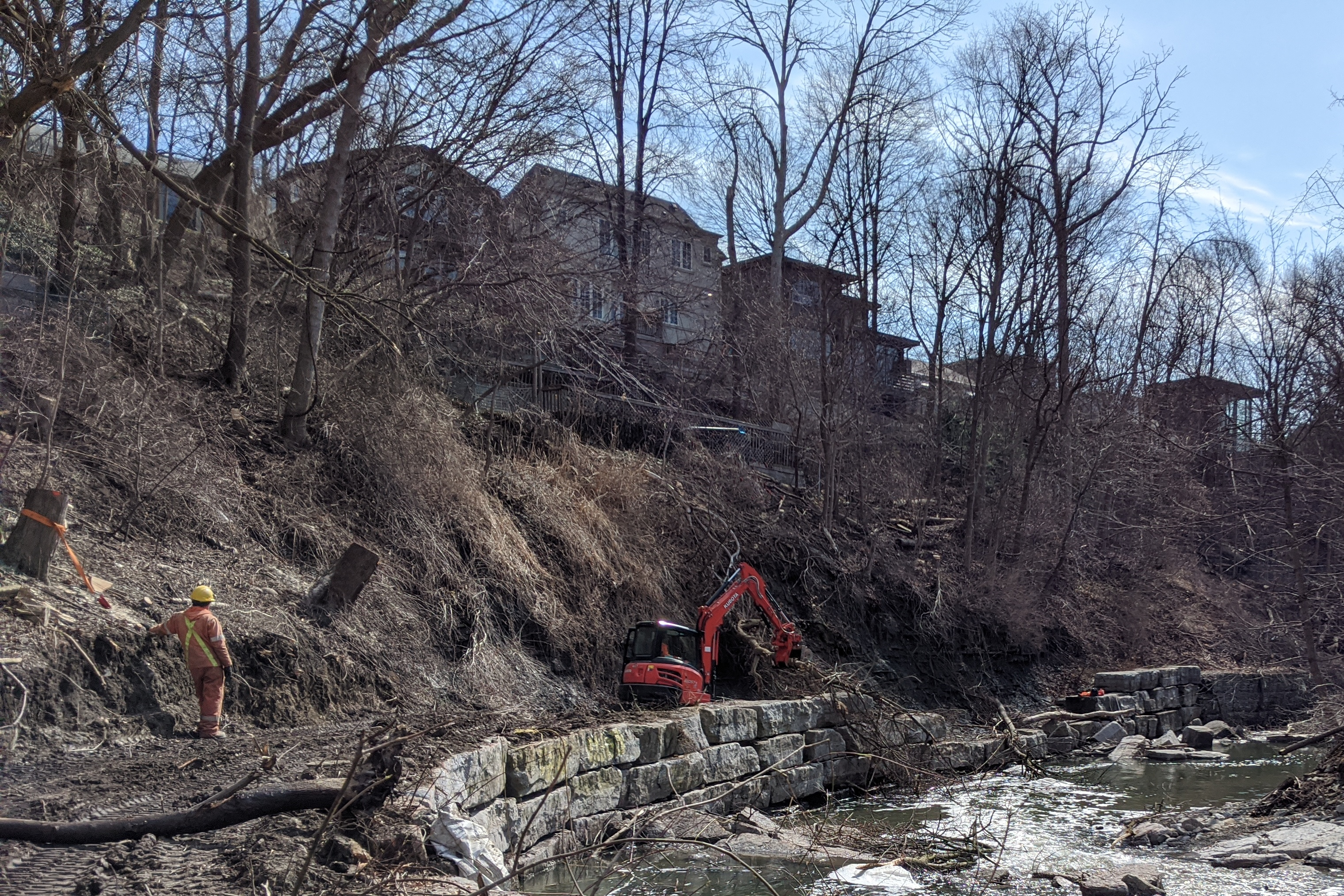 Workers removing felled trees from a construction site alongside Mimico Creek